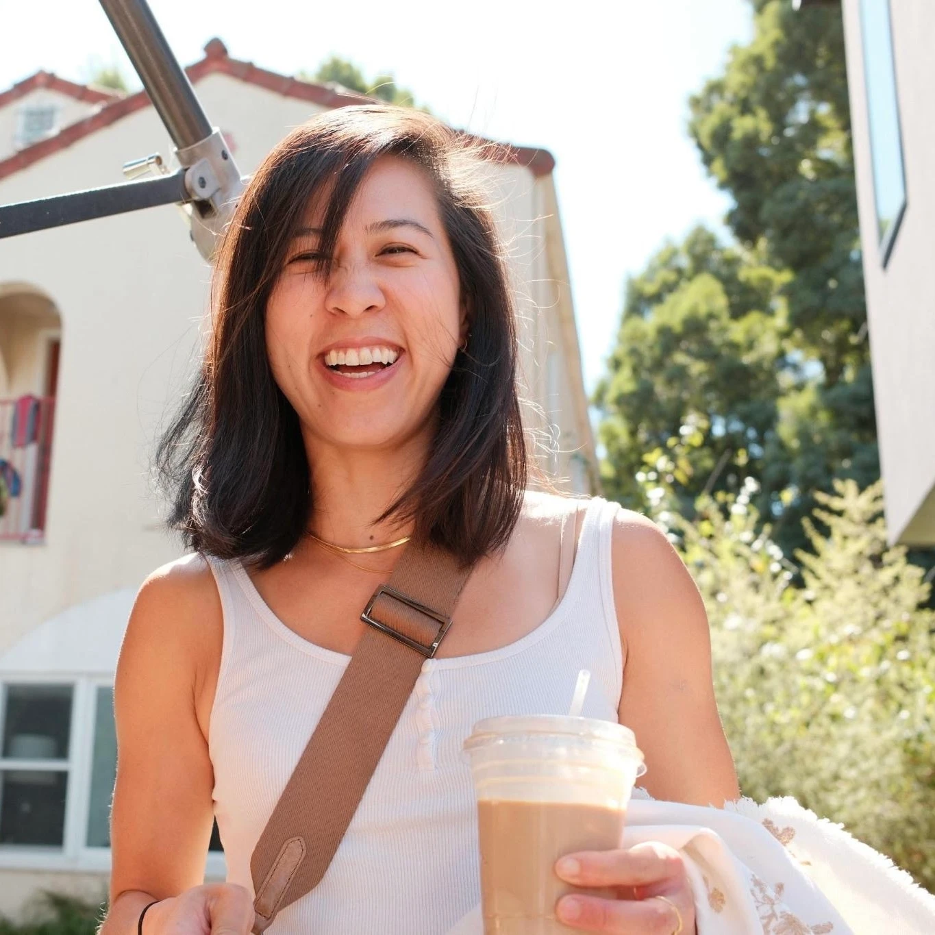 jen smiling outside on a sunny day, holding an iced coffee